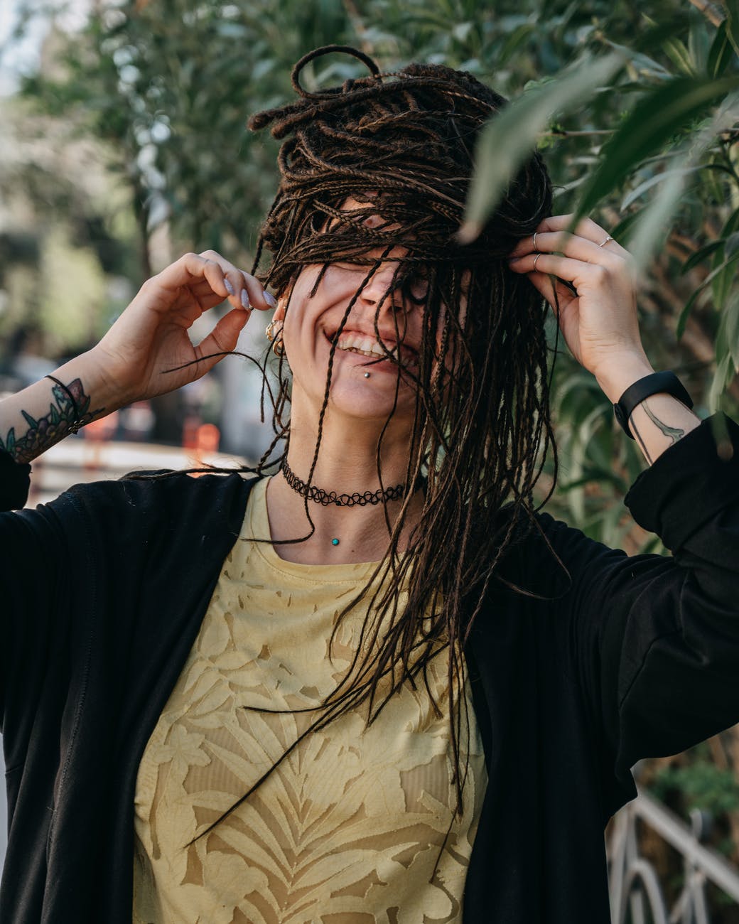 smiling woman with braids standing near green bush in daytime